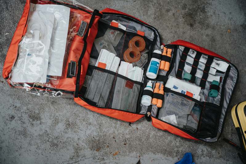 Two first responders reviewing travel insurance documents and a laptop showing a world map with highlighted countries